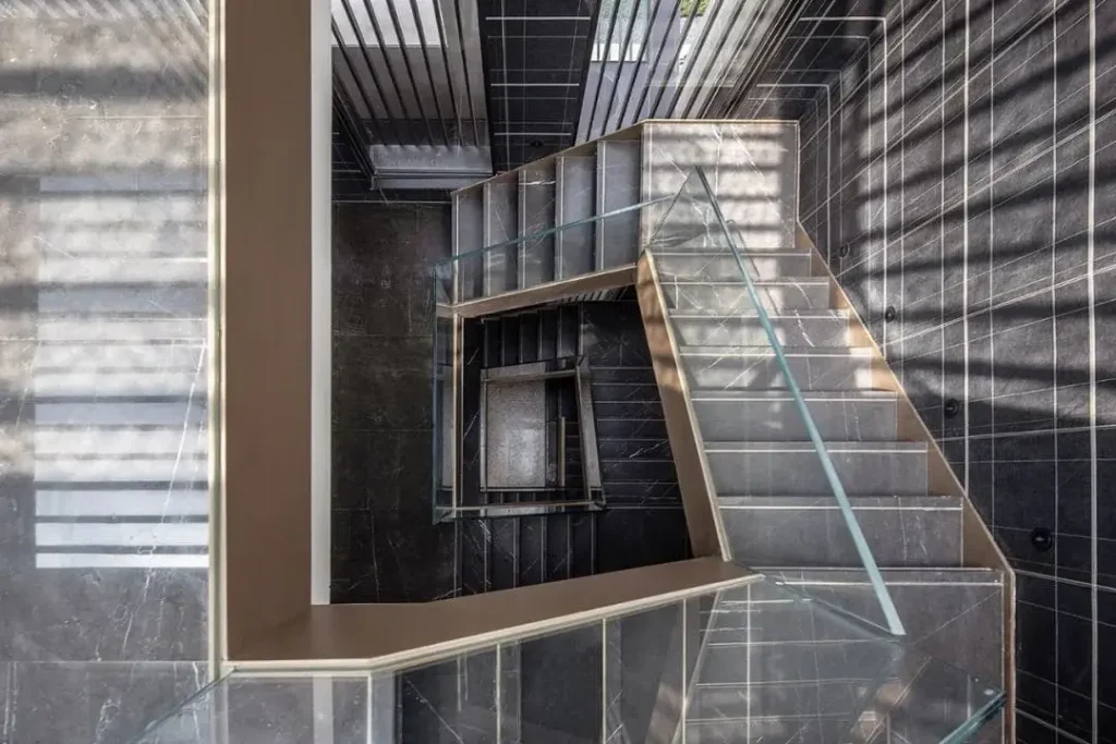 Residential stone staircase with clear treads and a continuous handrail