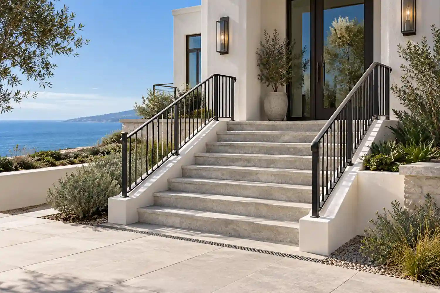 Exterior stone entry stair with dark metal guards beside a coastal home