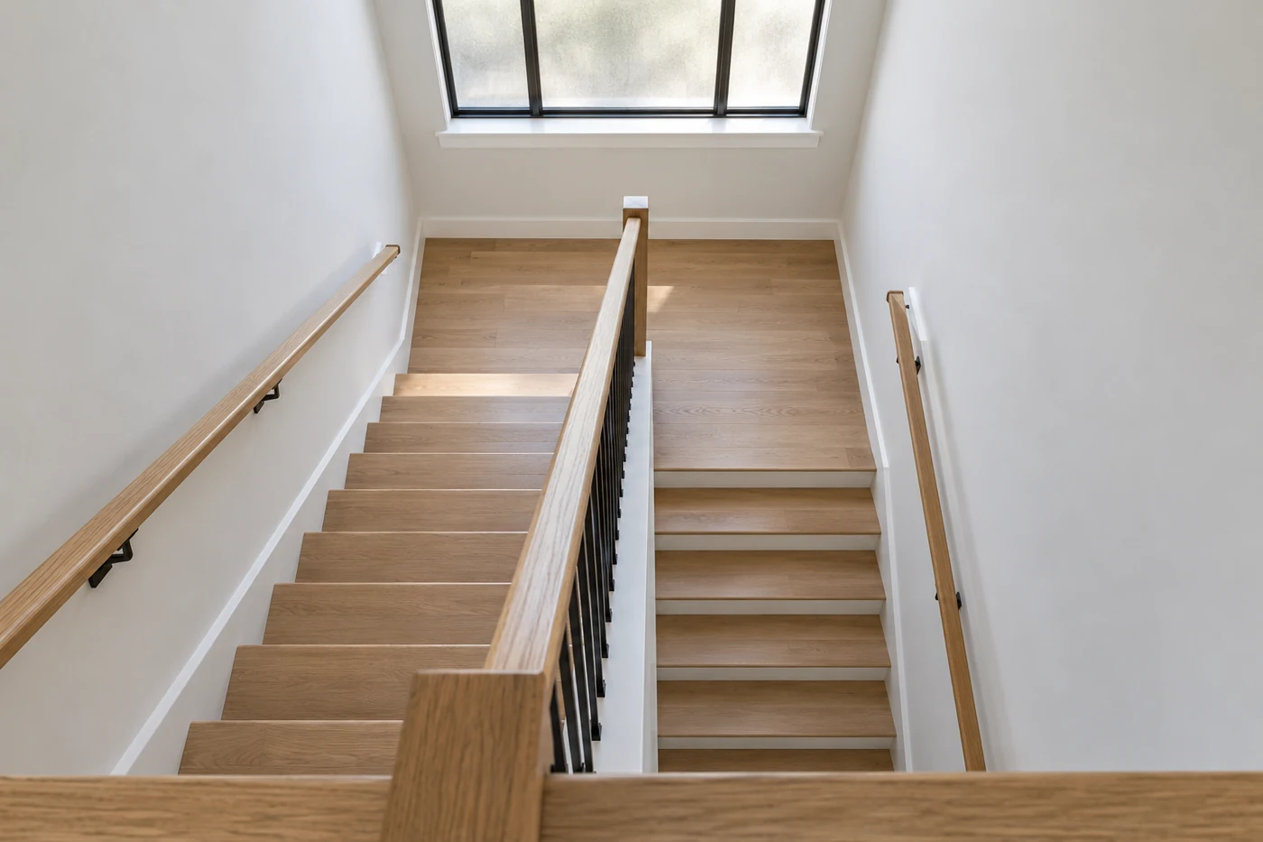 View down a compact U-shaped oak stairwell with a full intermediate landing